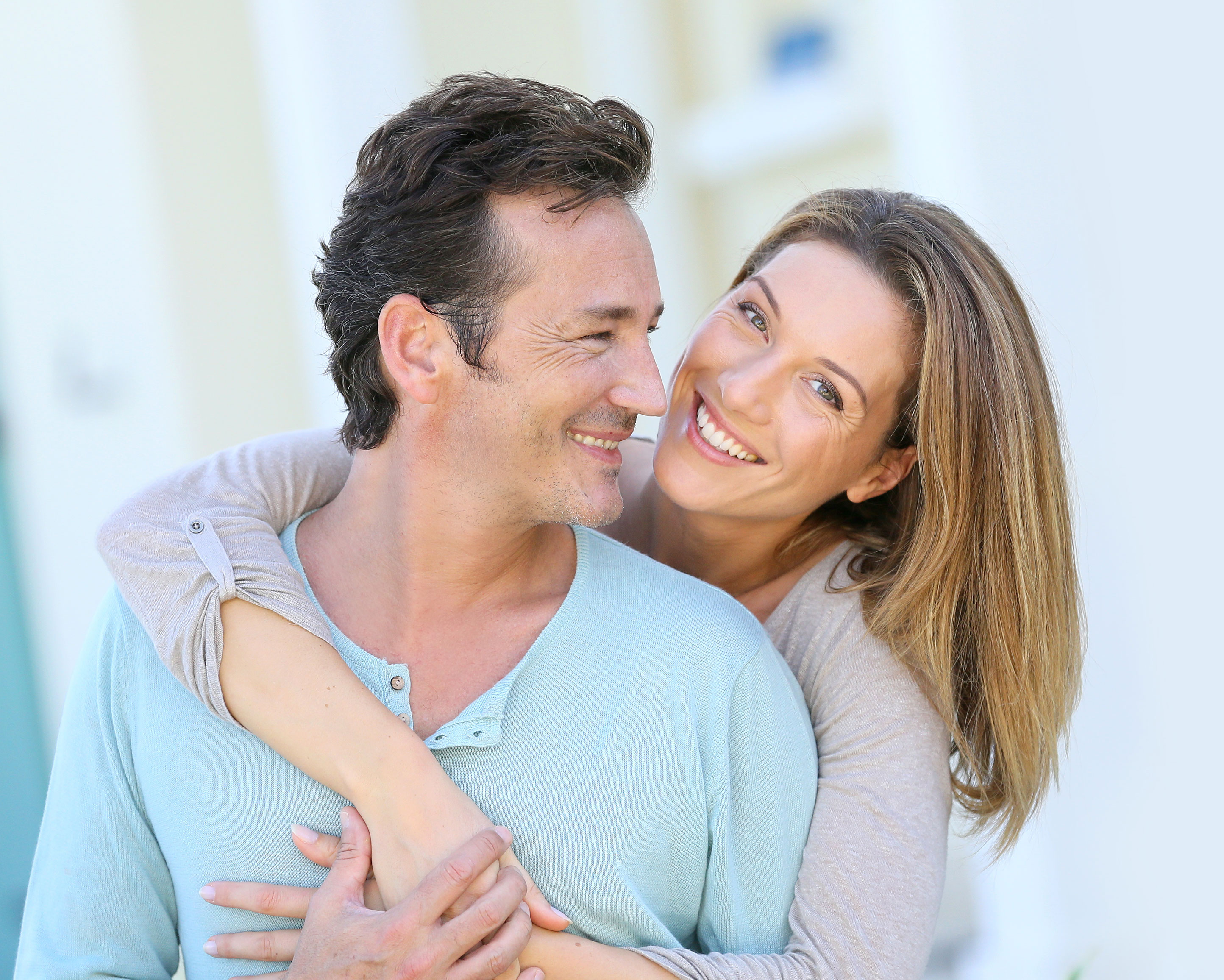 The image shows a man and woman embracing each other with smiles on their faces, suggesting a close relationship between them.