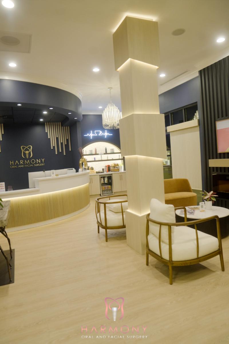 A modern interior space with a stylish seating area, a reception desk, and a coffee shop counter, featuring wood flooring and contemporary decor.