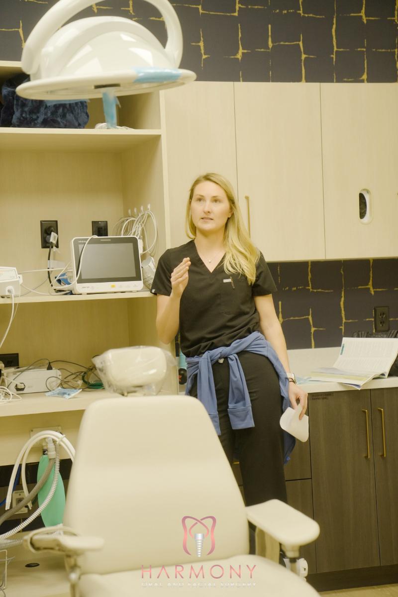 A woman stands in front of dental equipment in an office setting.