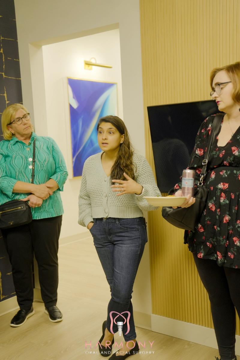 Three individuals standing in an indoor setting with a modern decor, engaged in conversation.