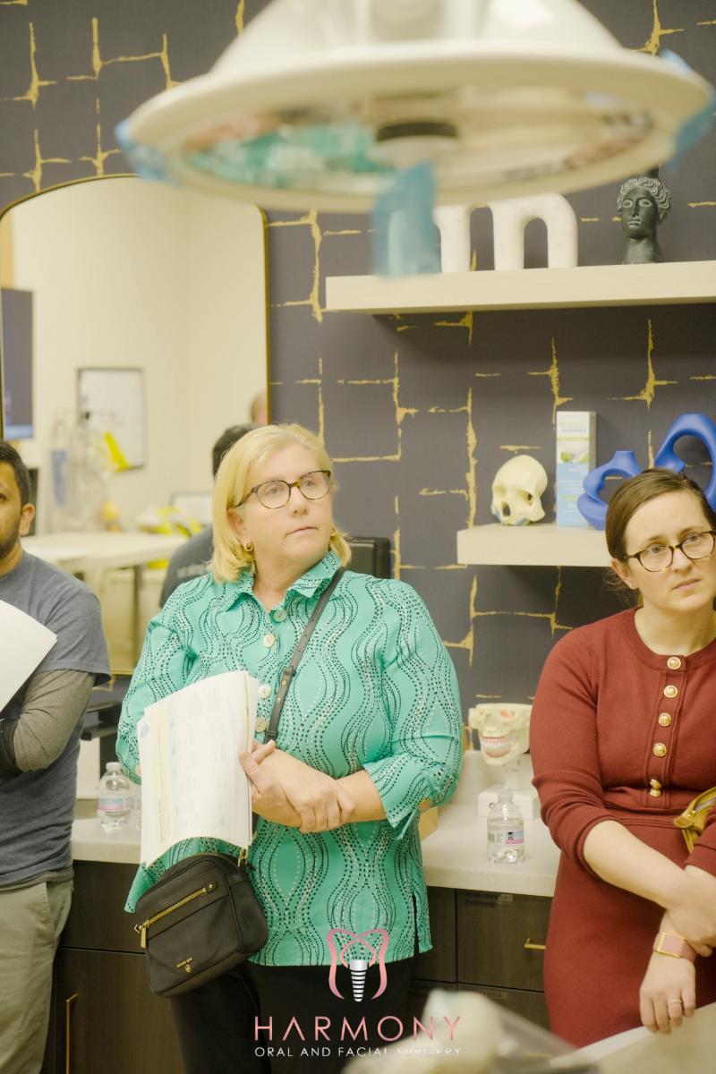 A woman stands next to a man in a store, with a shelf displaying various items behind them.