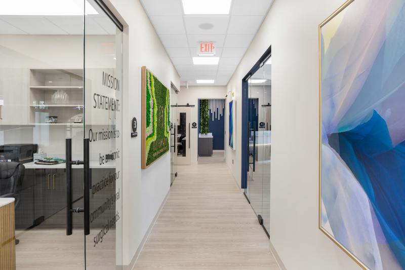 The image shows a modern office interior with contemporary artworks on the walls, professional furniture, and a clean, bright atmosphere.